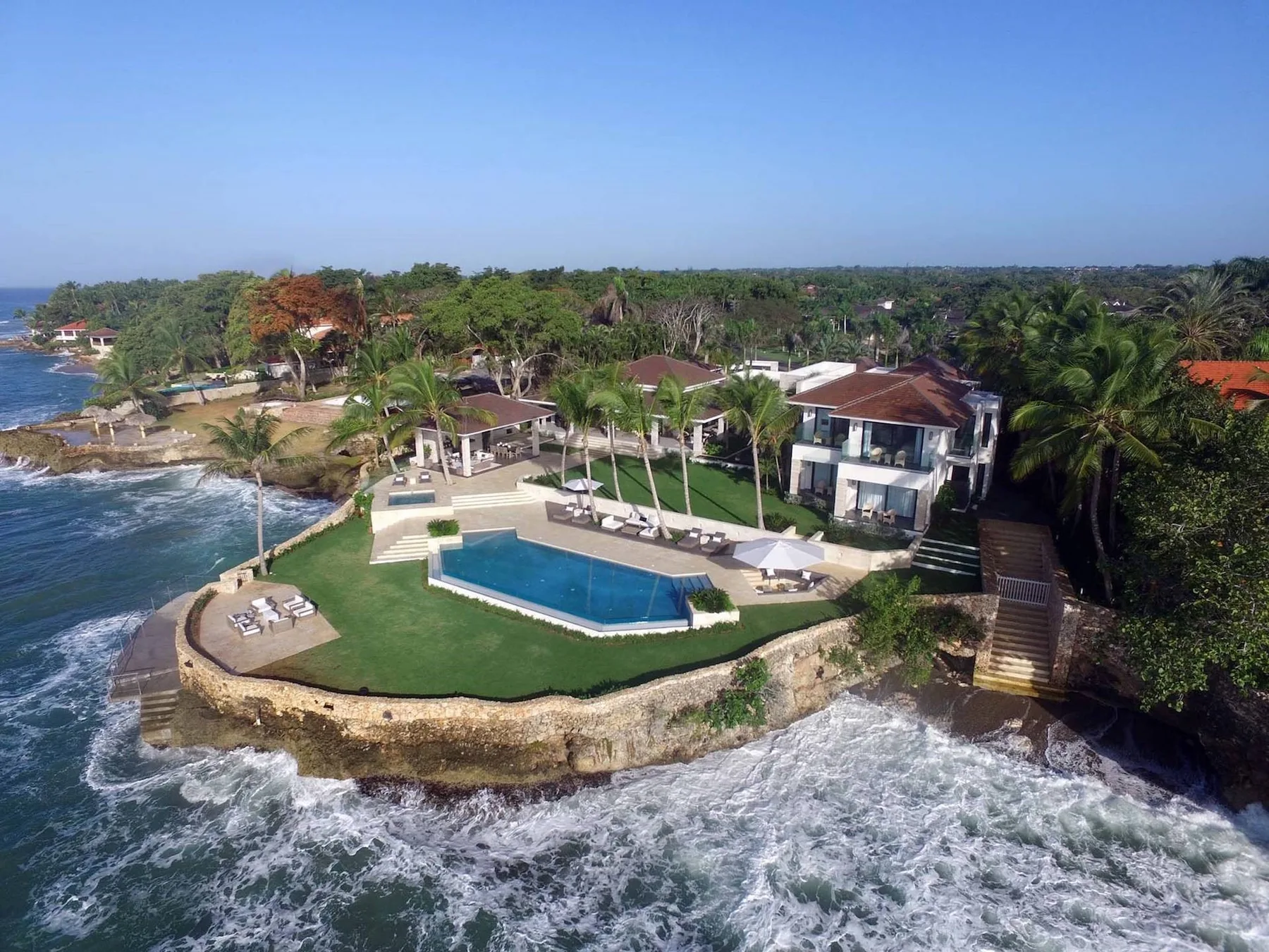 Aerial view of a coastal resort with a pool beside the ocean.