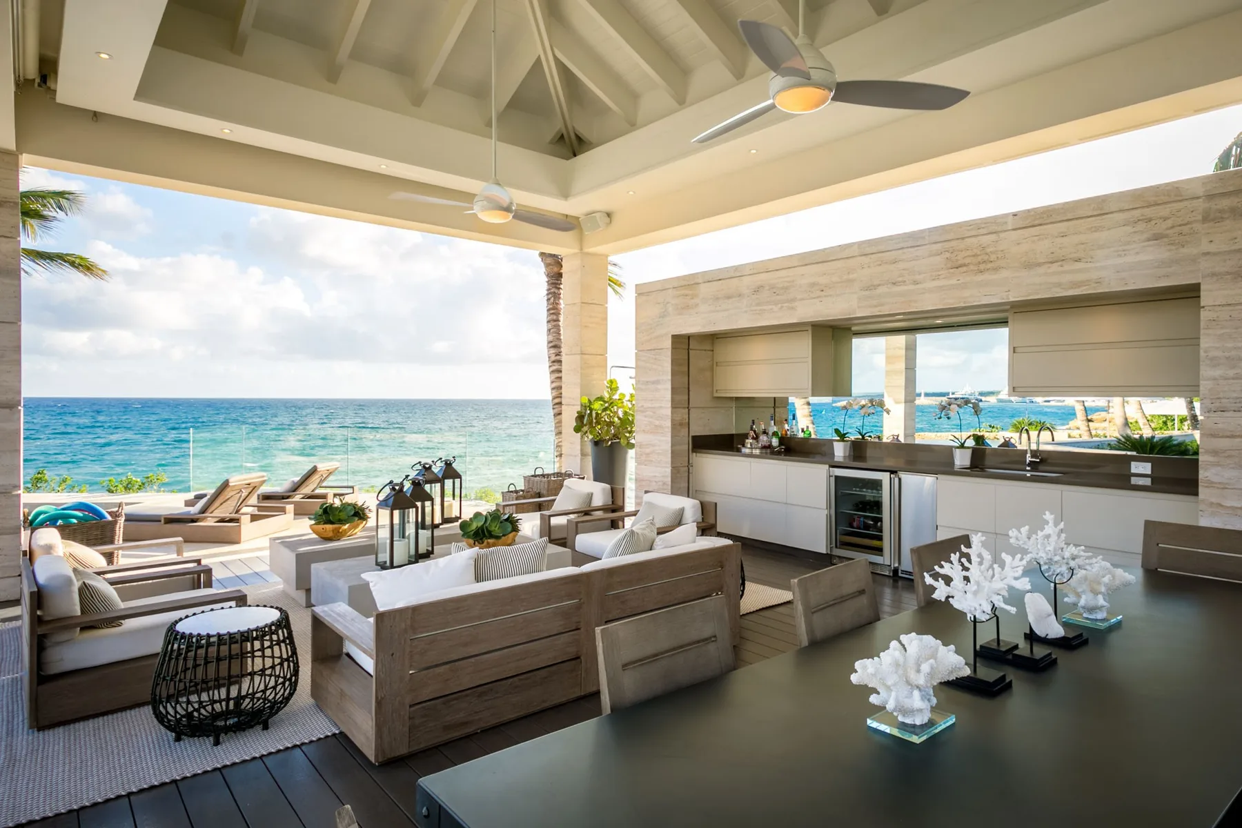 An open-air lounge with seating and a kitchen counter overlooks the ocean.