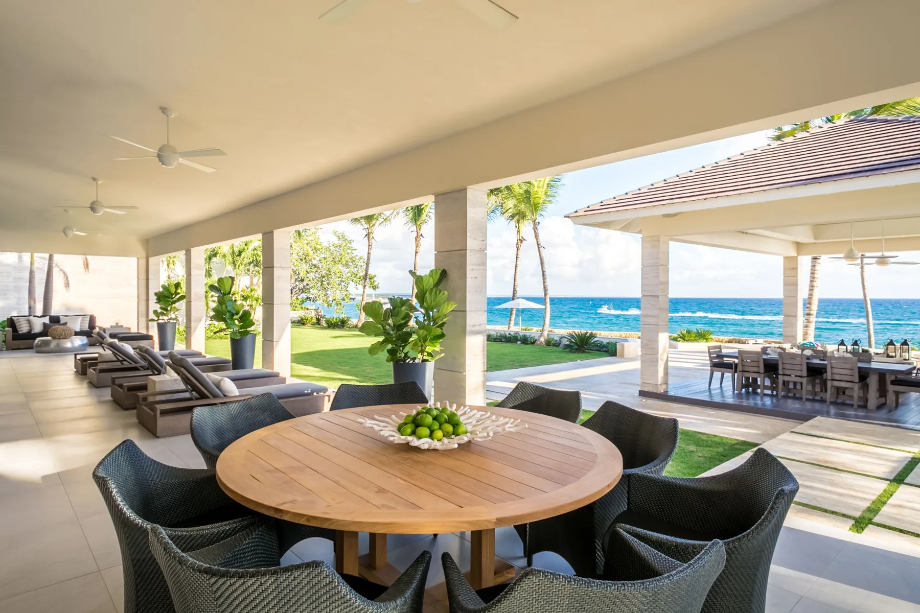 A covered patio with a round dining table overlooks the ocean.