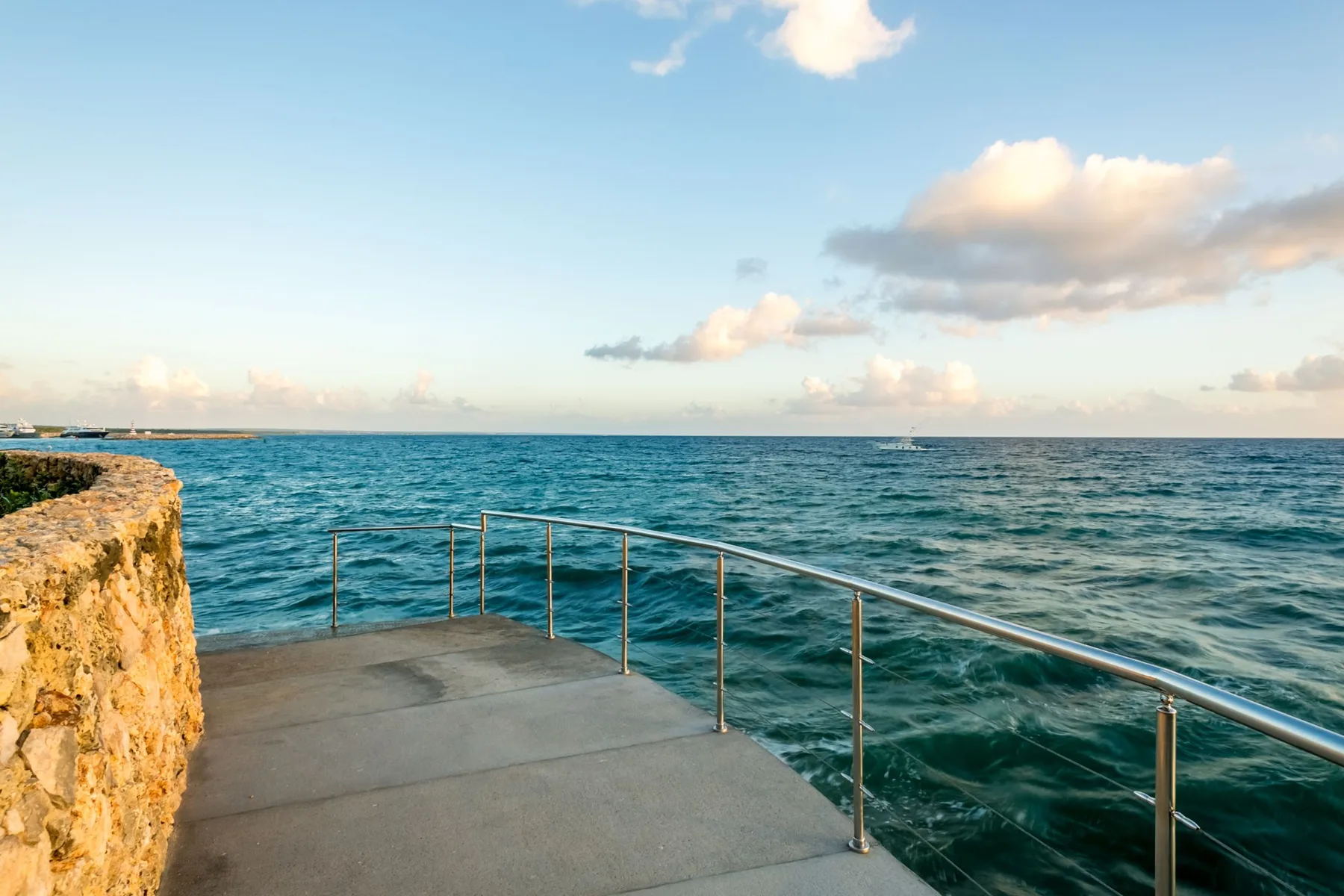 A seaside terrace overlooks the water beneath a partly cloudy sky.