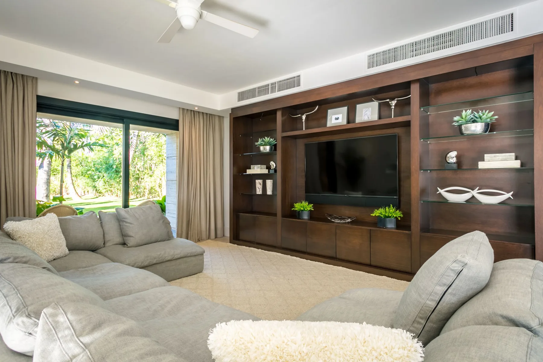 A living room with gray seating and a television set in built-in shelving.