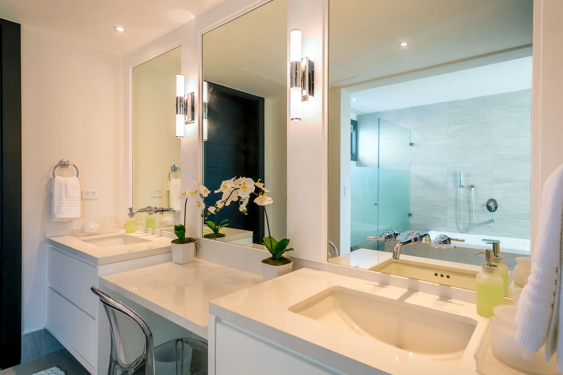 A bathroom vanity with sinks and mirrors overlooks a glass shower.