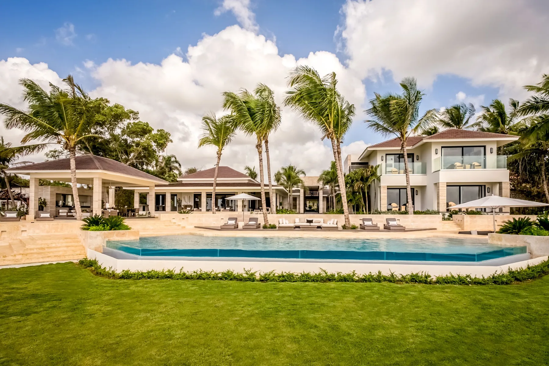 A landscaped resort pool sits in front of low-rise buildings and palm trees.