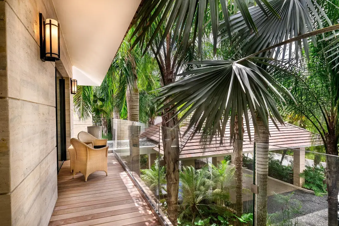 A covered outdoor walkway with wooden decking overlooks a lush garden.