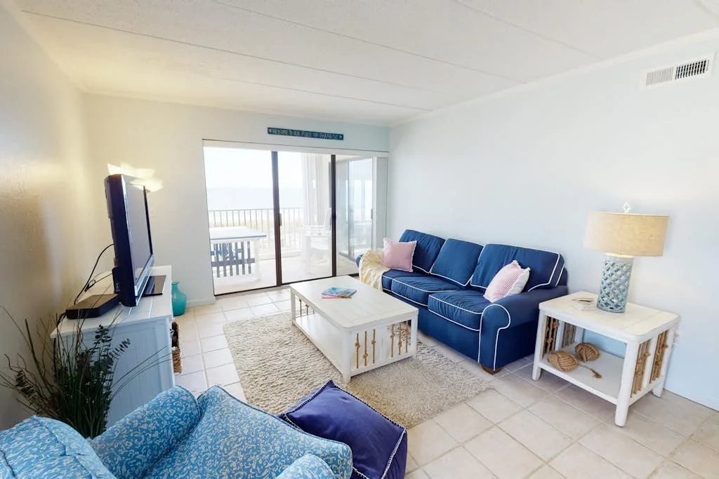 A bright living room has blue seating around a coffee table beside glass doors.