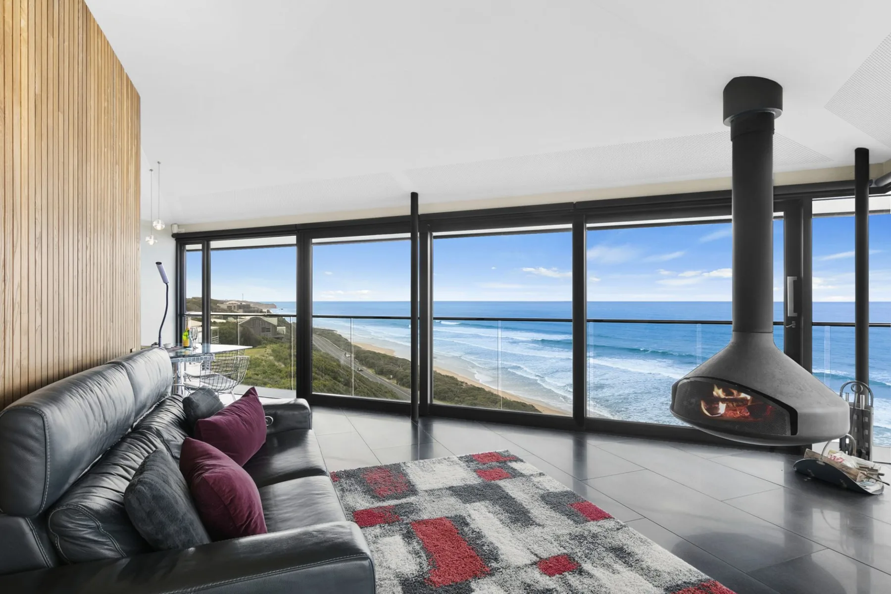 A living room with seating and wide windows overlooking the ocean.