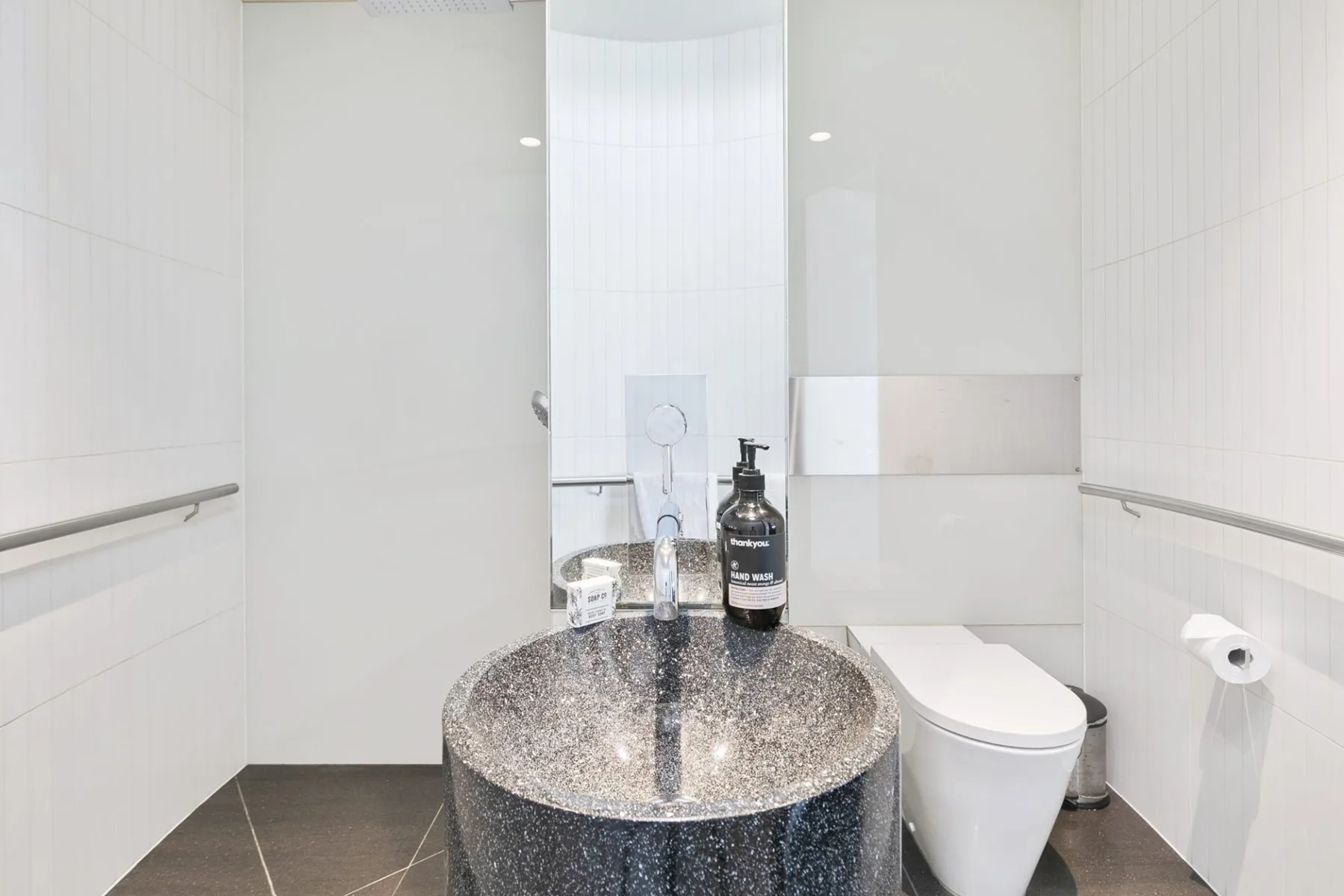 A bright bathroom with a rounded sink and toilet.