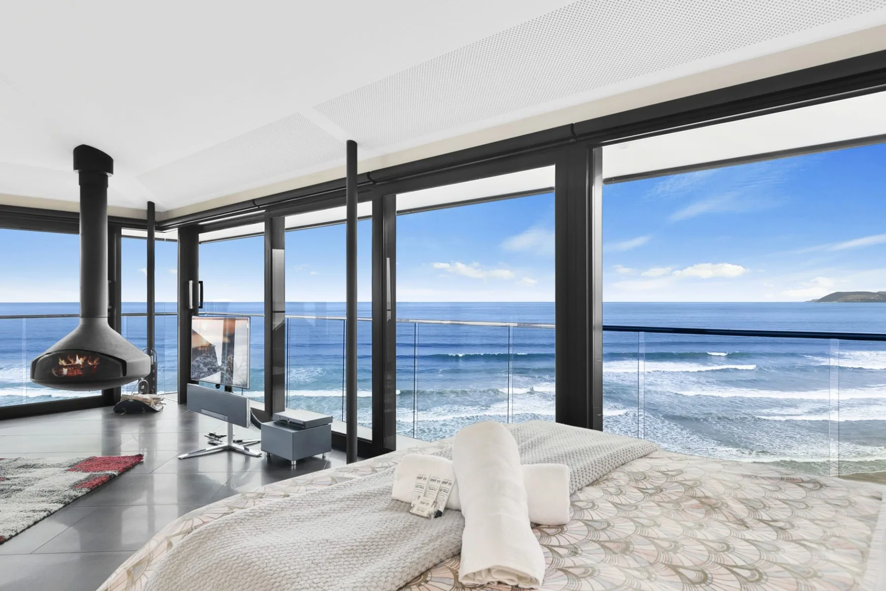 A modern bedroom with floor-to-ceiling windows overlooking the ocean.