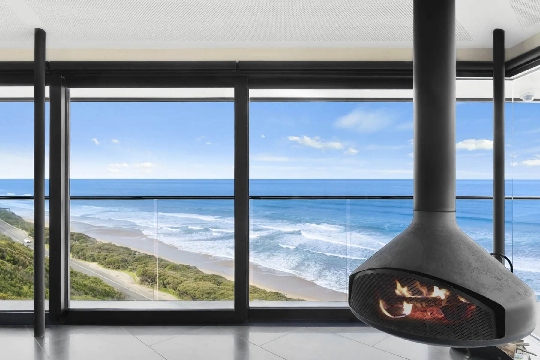 A living area with a suspended fireplace overlooking the ocean.