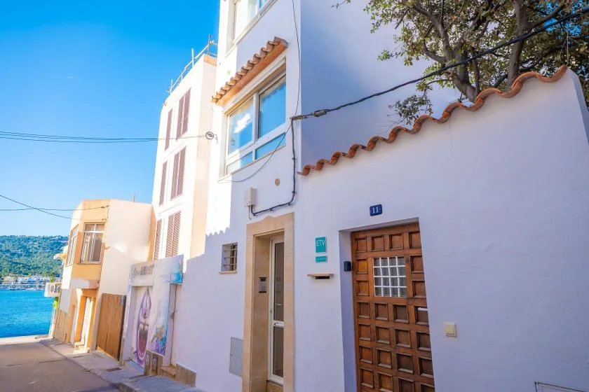 Una calle soleada con edificios blancos y vistas al mar.