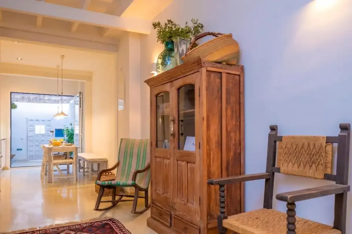 Una luminosa sala de estar y comedor con asientos de madera y un armario con puertas de vidrio.
