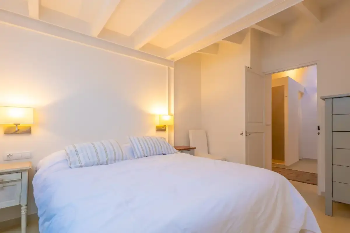 Un dormitorio con una cama grande bajo vigas expuestas en el techo.