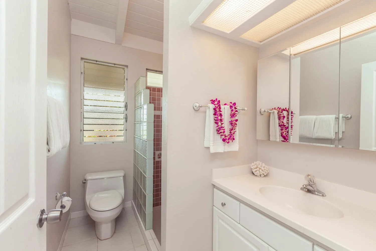 A bright bathroom with a vanity, large mirror, and toilet.