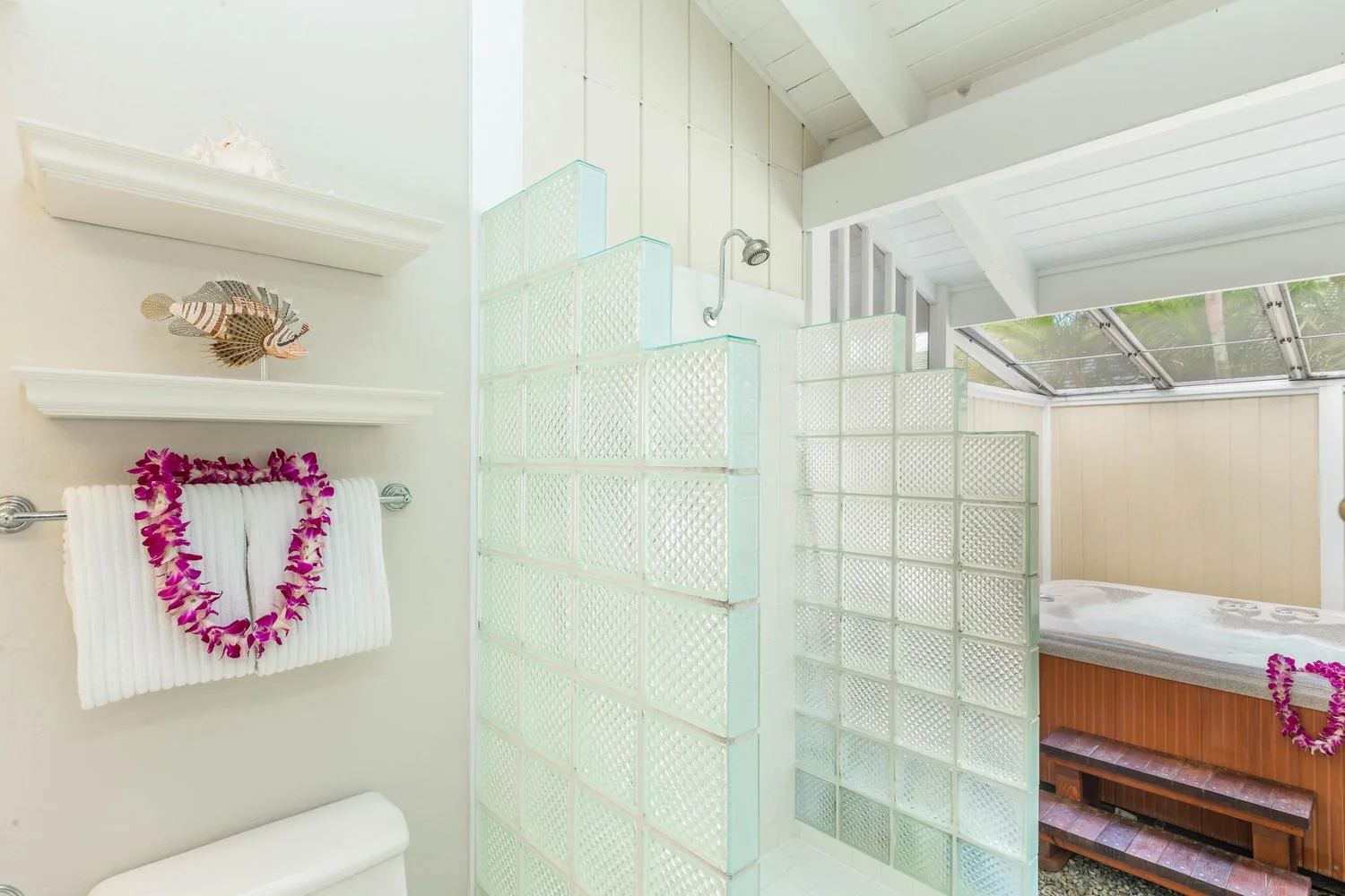 A bright bathroom has glass-block partitions and a shower beside a soaking tub.