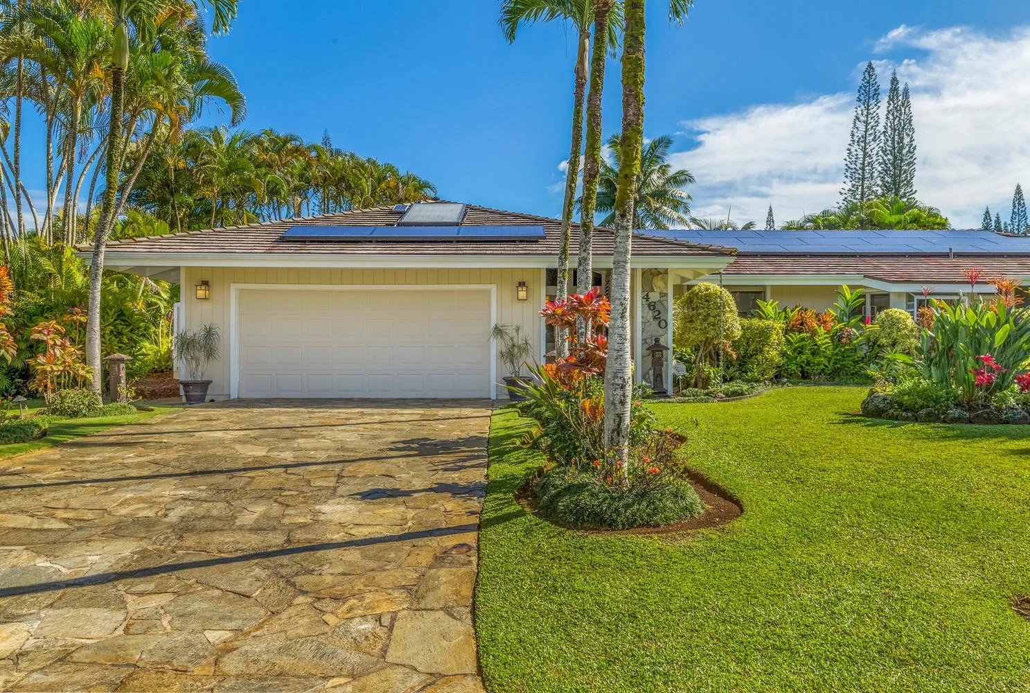 A single-story house with a stone driveway, garage, and landscaped lawn.