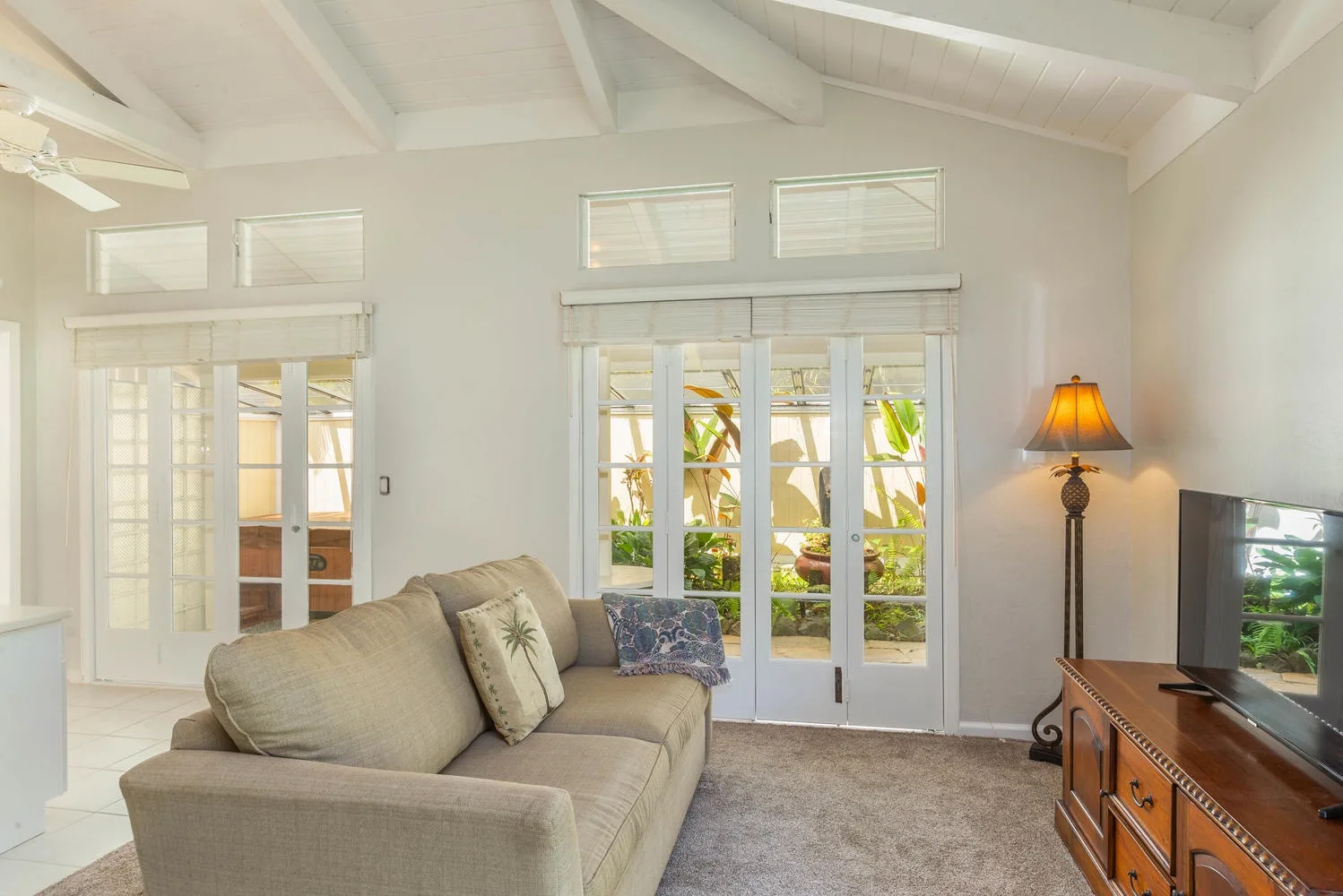 A bright living room with seating, glass doors, and a floor lamp.