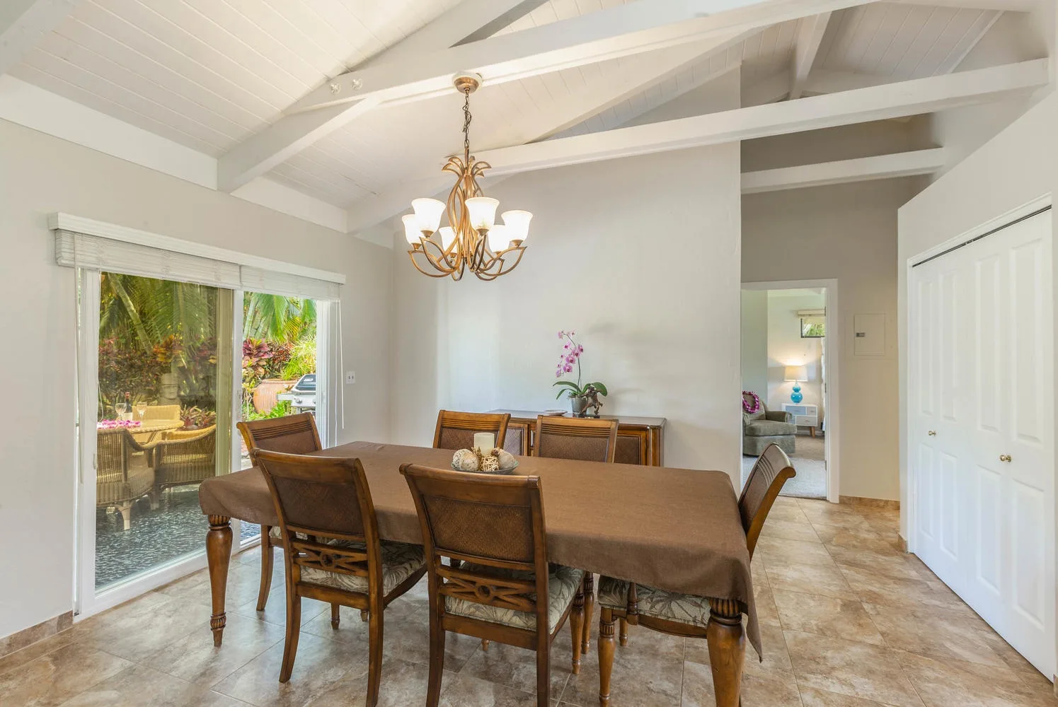A dining area with a long table and chairs beneath a chandelier.