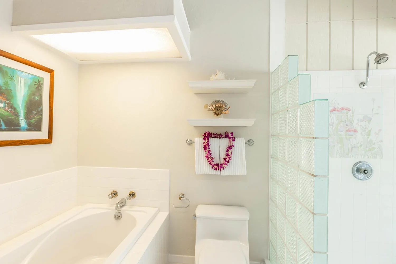 A bright bathroom with a bathtub, toilet, and tiled shower area.