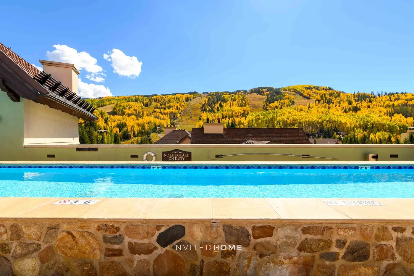 Una piscina al aire libre tiene vistas a una colina cubierta de árboles otoñales.