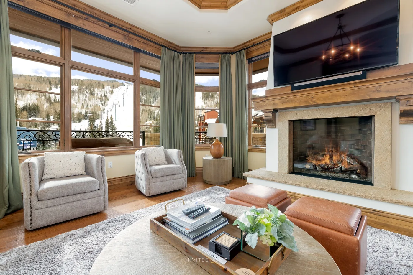 Una sala de estar con grandes ventanas que dan a un paisaje nevado y una chimenea.