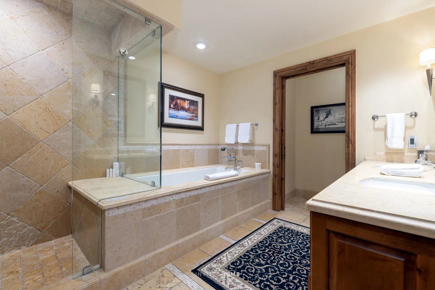 Un baño con ducha de vidrio, bañera revestida de azulejos y lavabo con mueble.