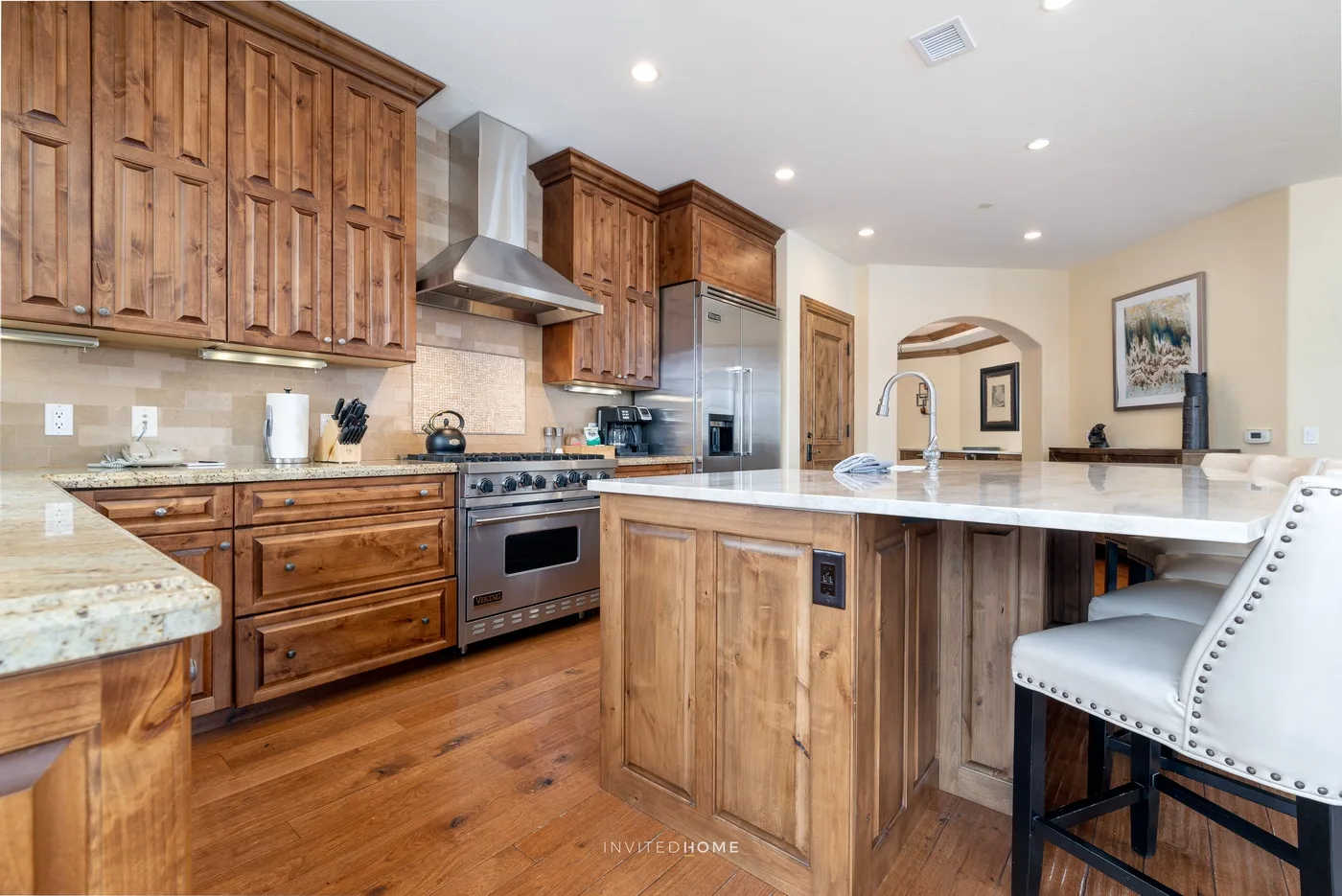 Una cocina con gabinetes de madera, electrodomésticos de acero inoxidable y una isla central.