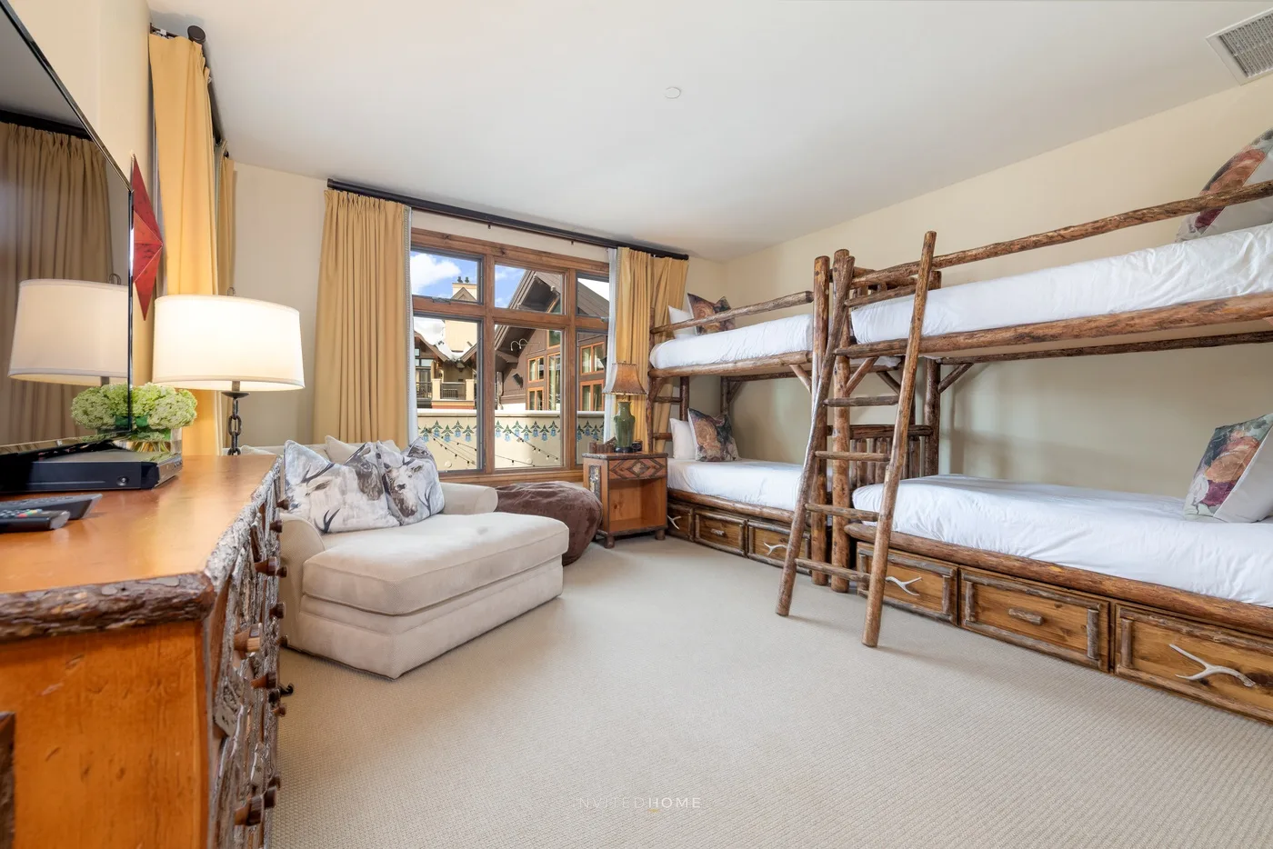 Dormitorio con literas, una zona de estar y ventanas grandes.