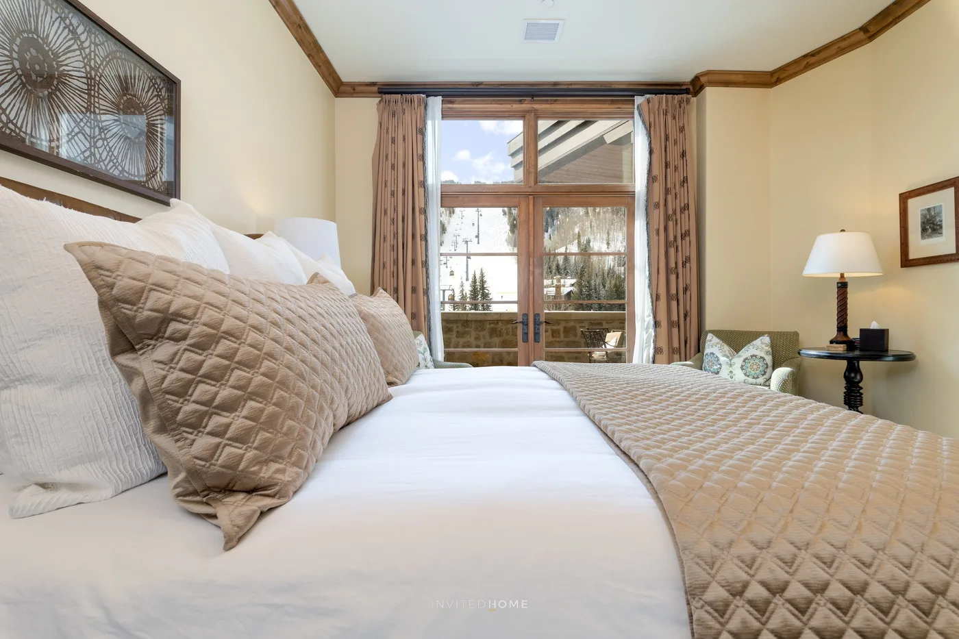 Un dormitorio con una cama bien hecha y puertas de vidrio que dan a un balcón.