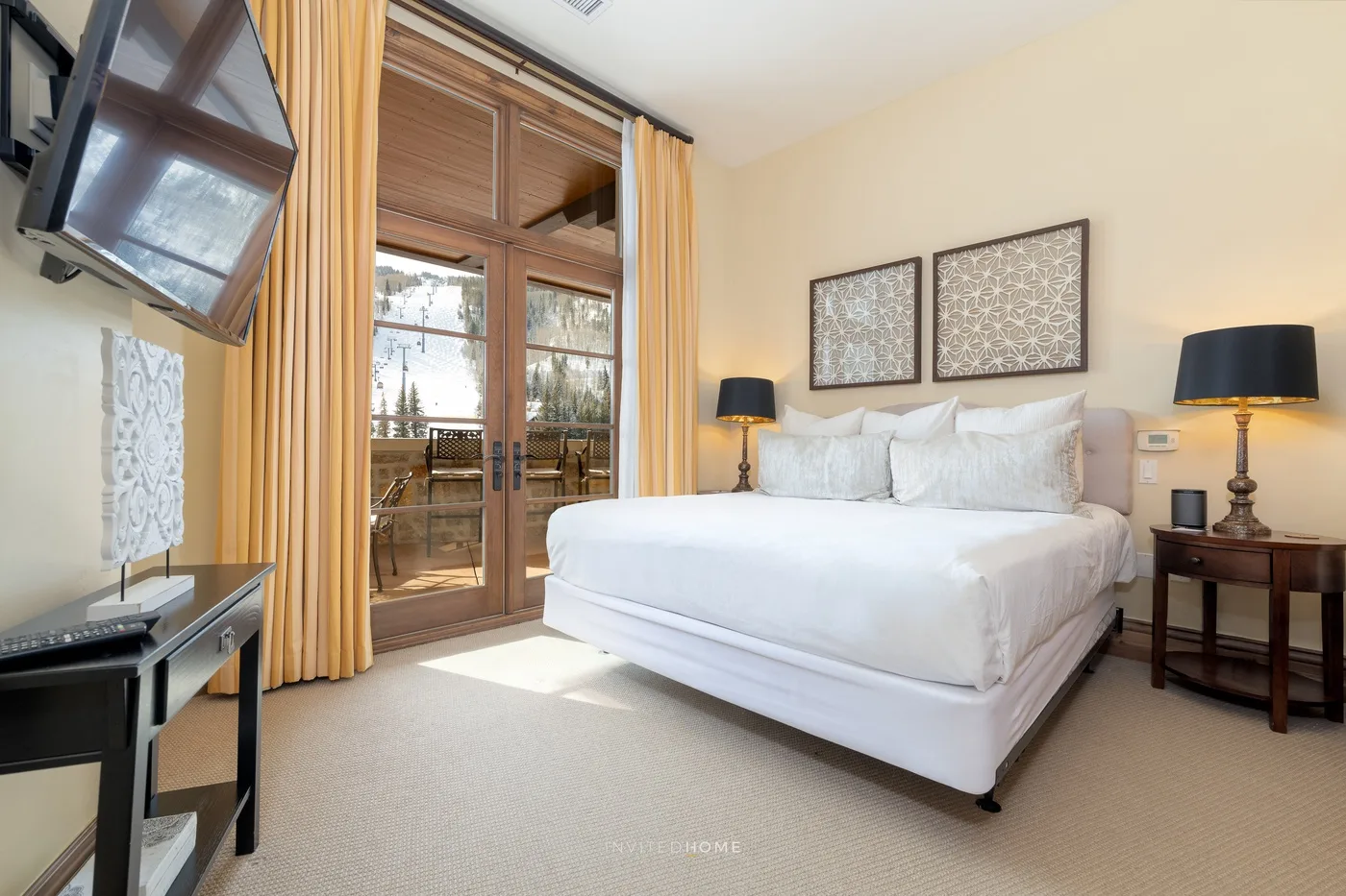 Un dormitorio con una cama grande, lámparas de mesilla y puertas de vidrio que dan a un balcón.