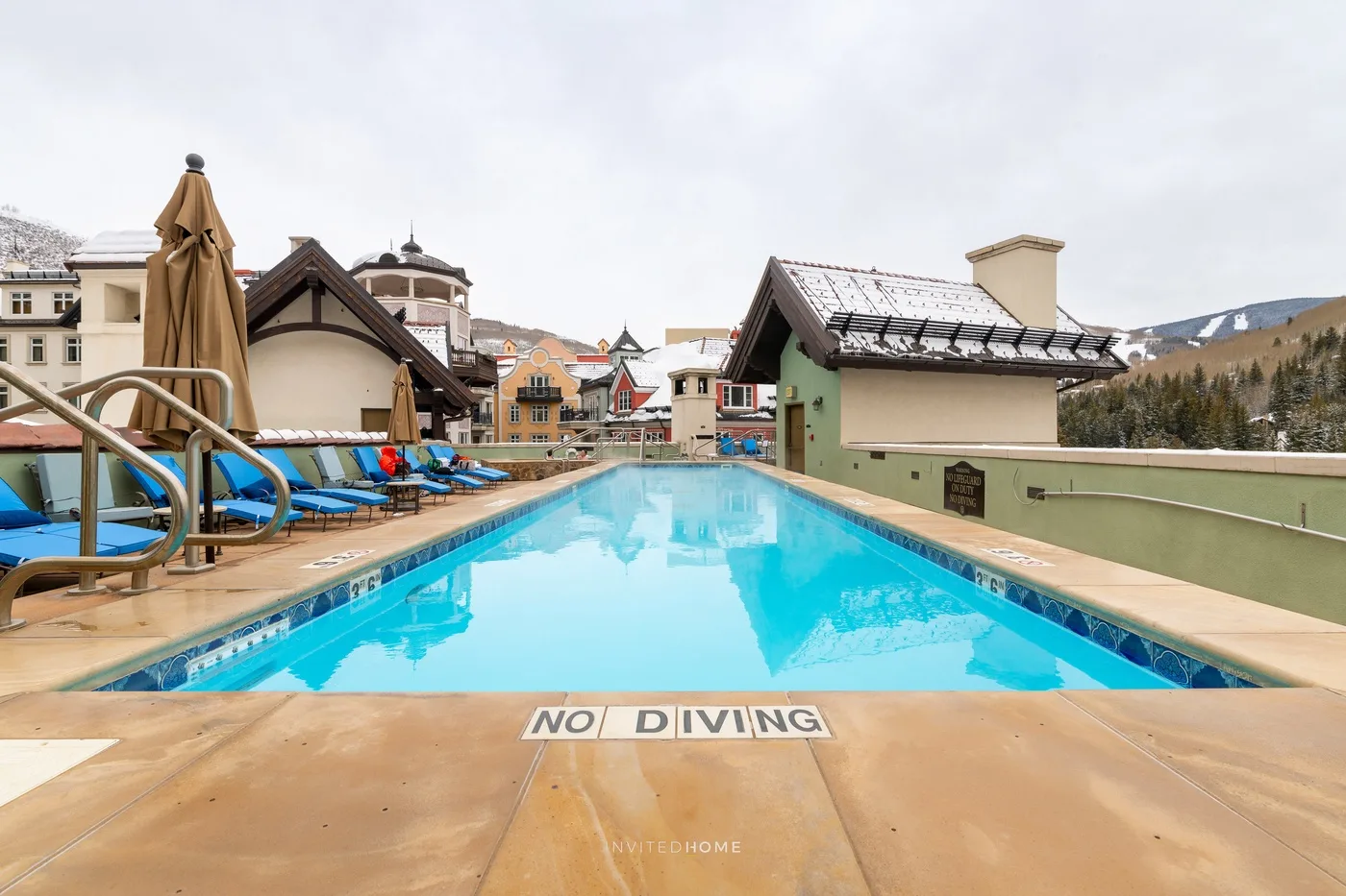 Una piscina al aire libre está junto a edificios, con asientos en la terraza.