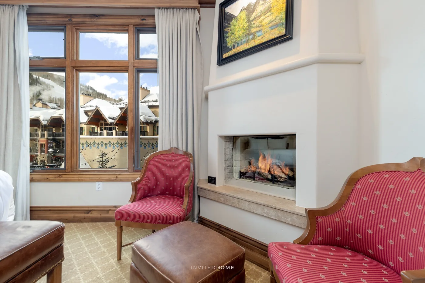 Una sala de estar con asientos rojos, una chimenea y una ventana grande.