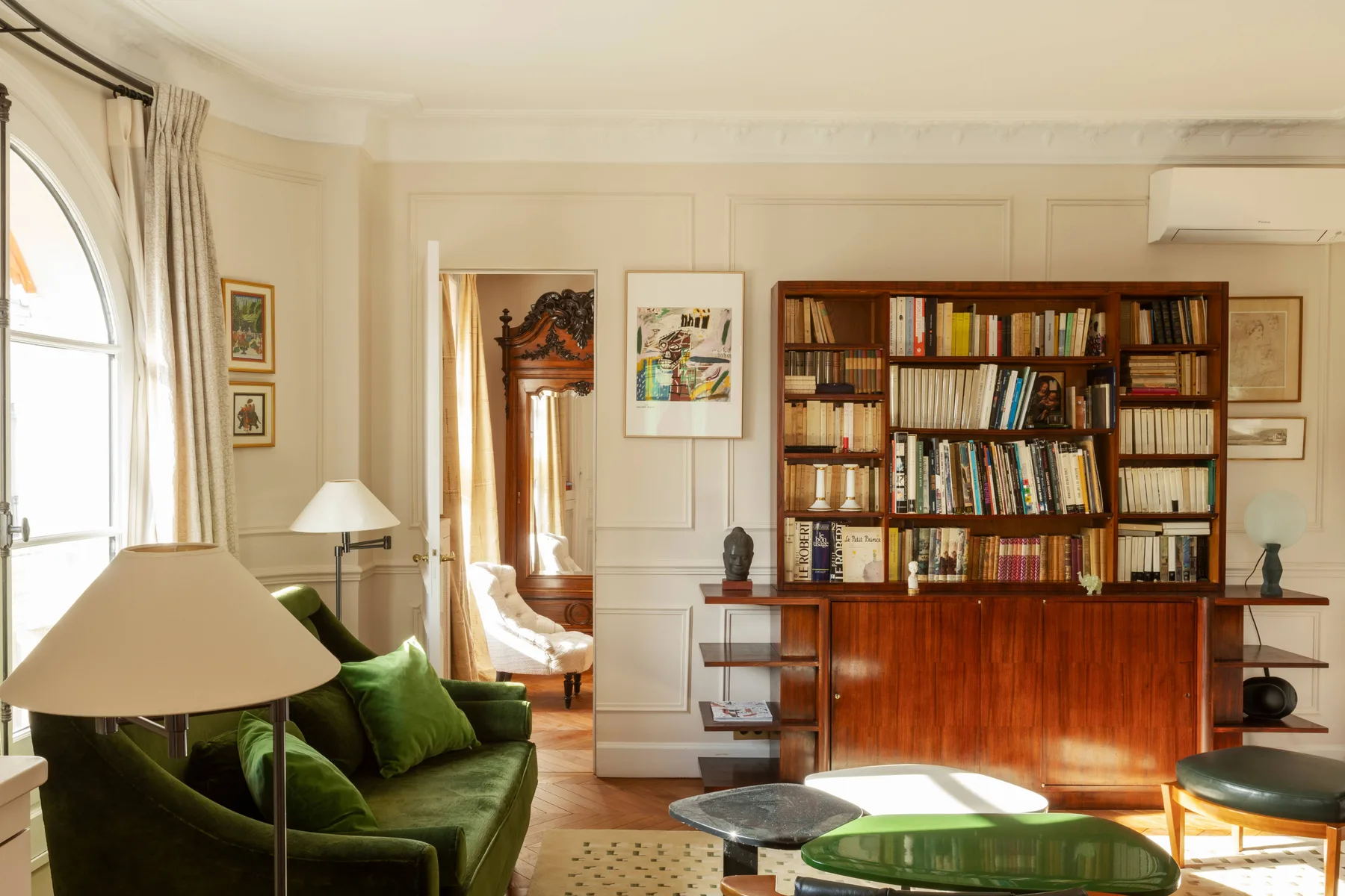 Una sala luminosa con asientos verdes y una gran estantería de madera.