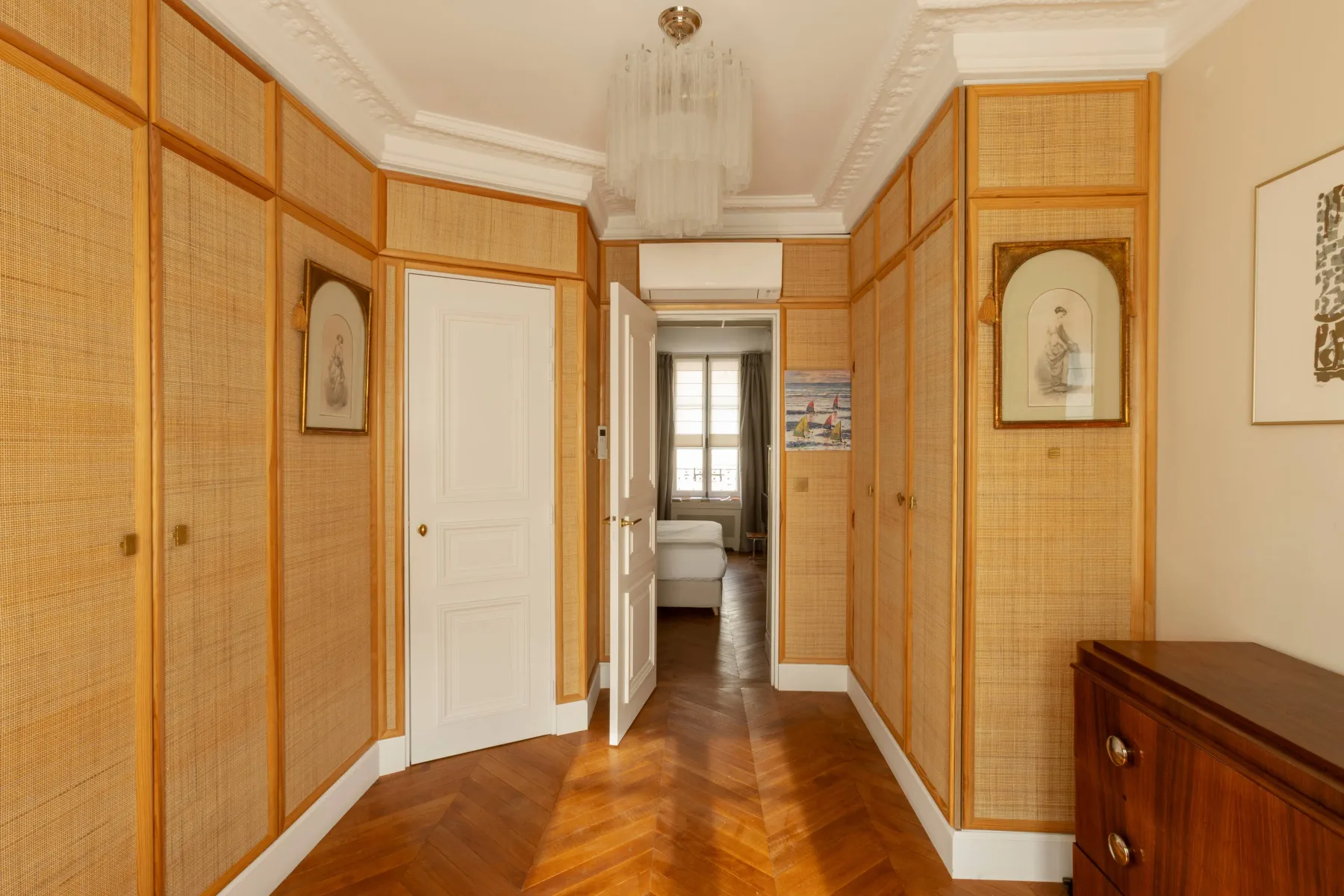 Un pasillo con paneles tejidos conduce a una habitación luminosa.