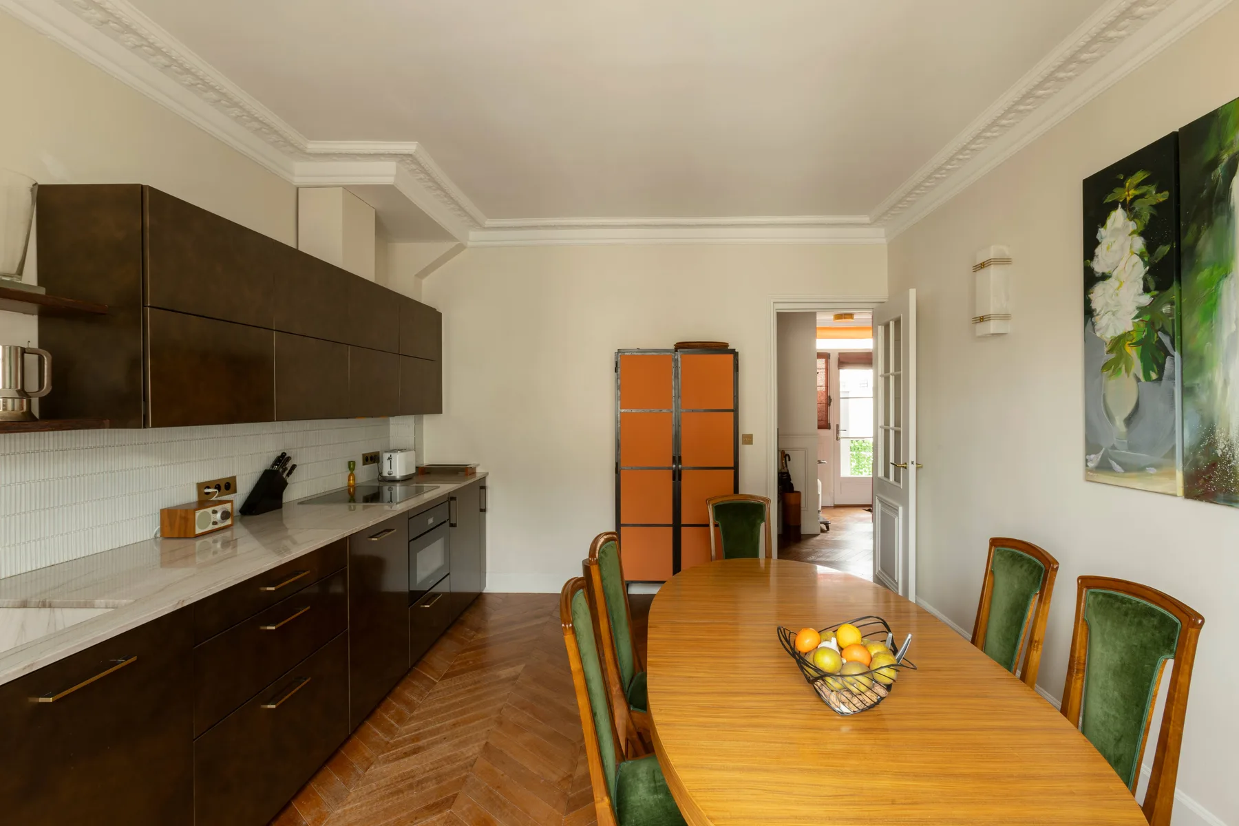 Un comedor con una mesa de madera y sillas junto a una cocina oscura.
