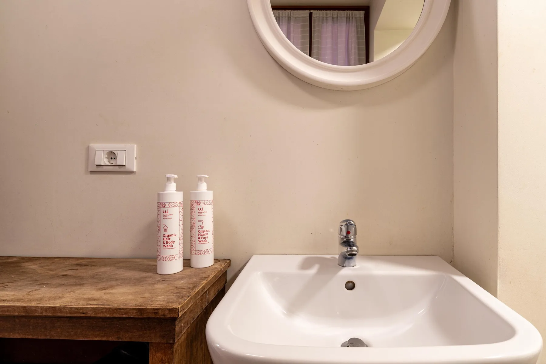 A bathroom vanity with a white sink, wall mirror, and two bottles.