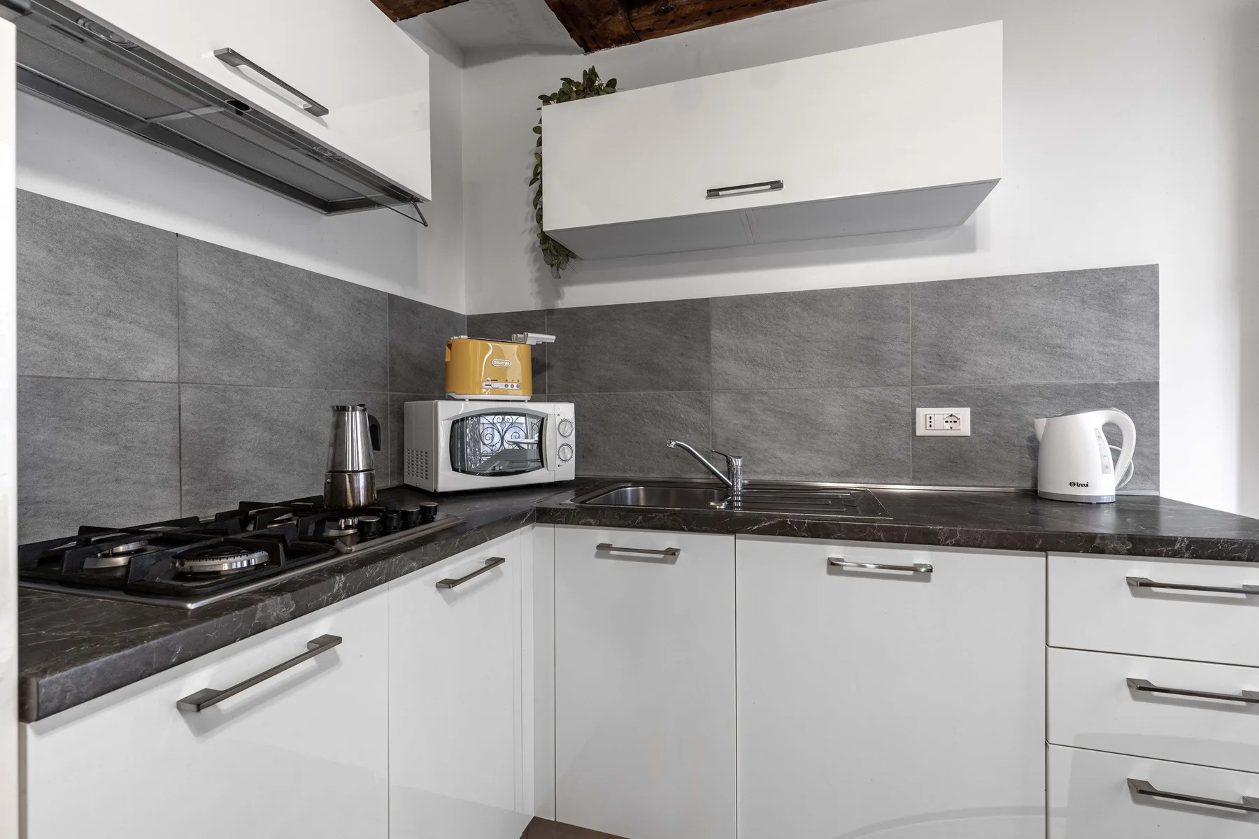 A modern kitchen with gray backsplash tiles and white cabinets.