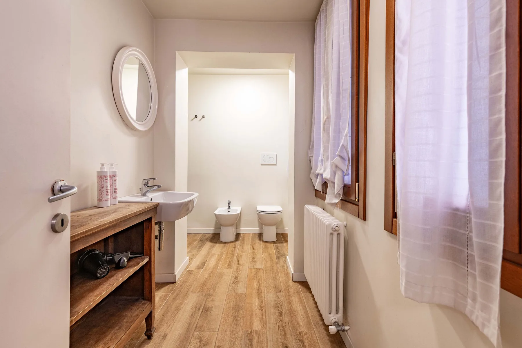 A bathroom with a wooden vanity, sink, and toilet.