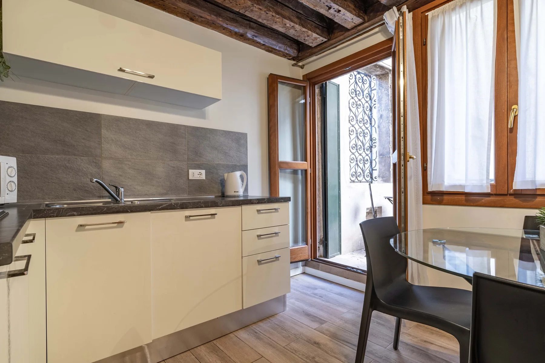 A compact kitchen and dining area with a counter and glass table.