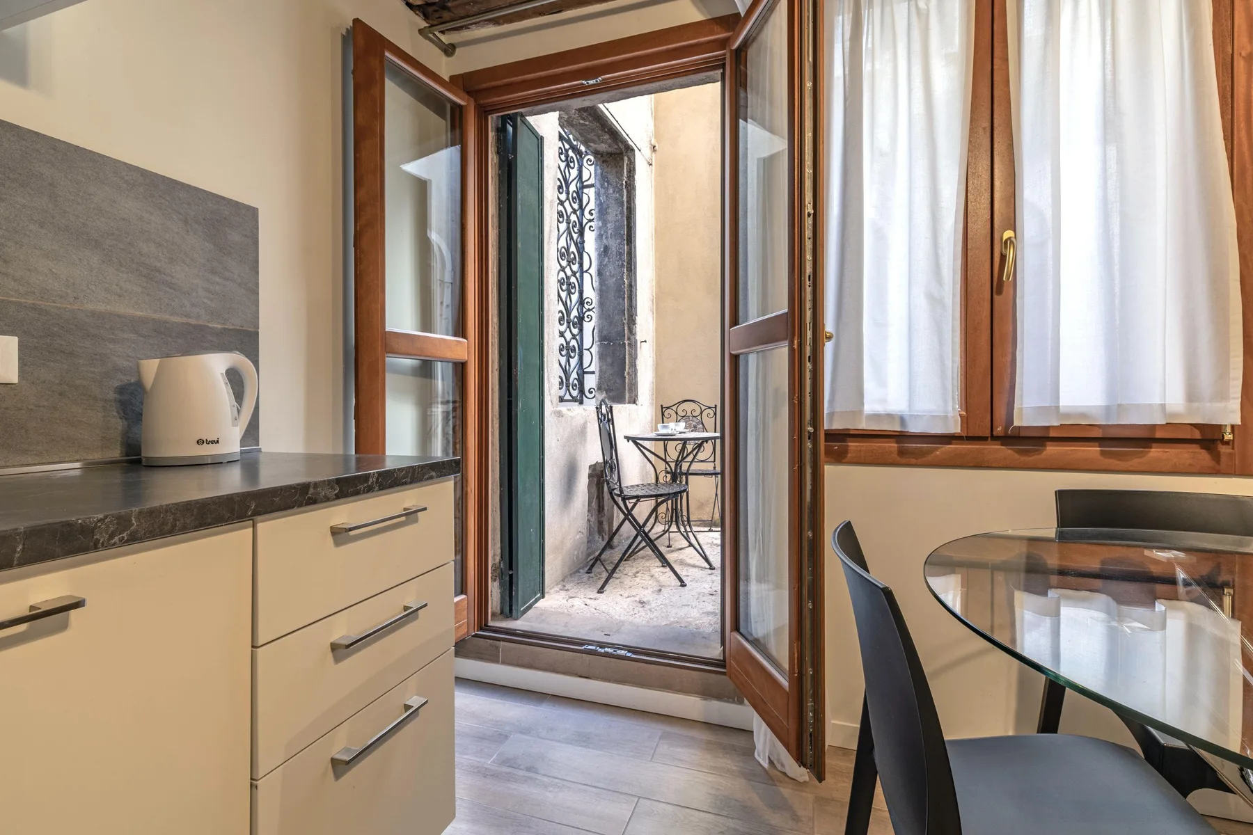 A dining area opens through glass doors to a small patio with seating.