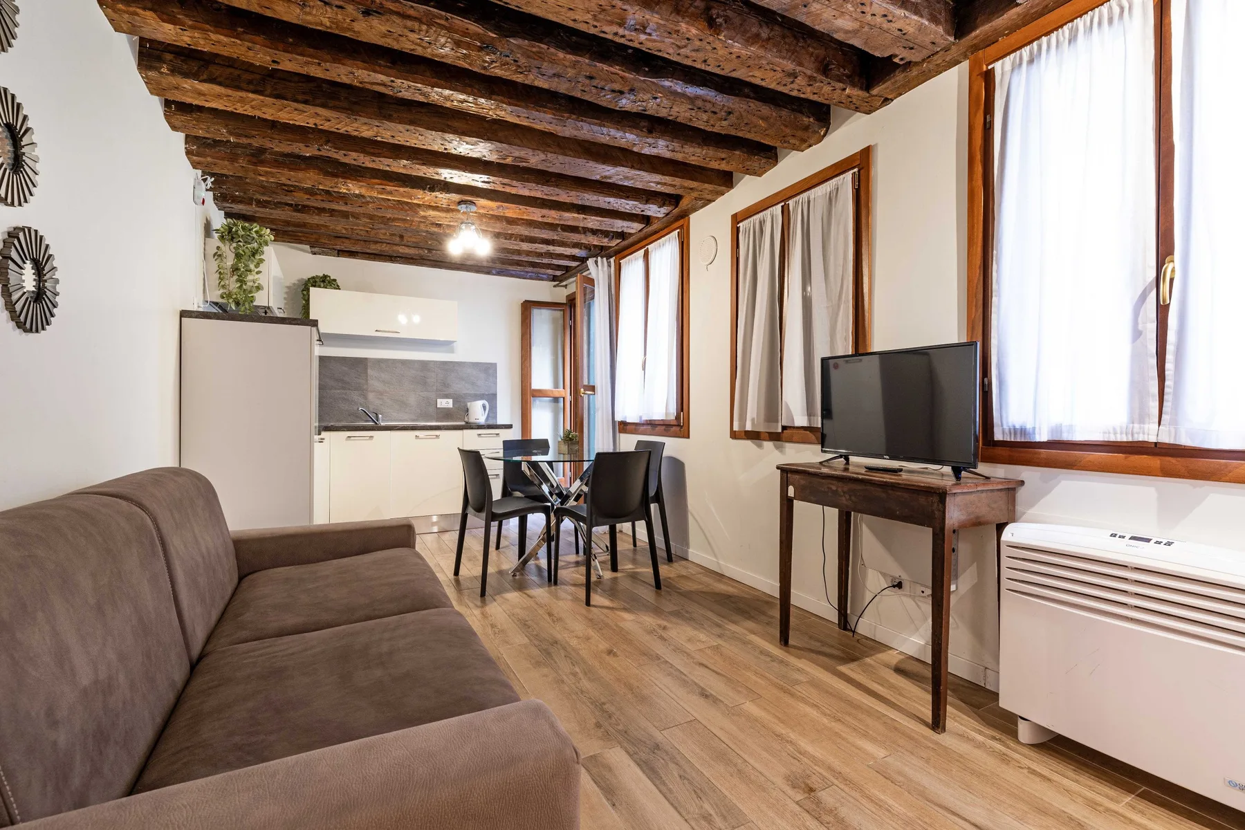 A living area with seating, a dining table, and a compact kitchen.