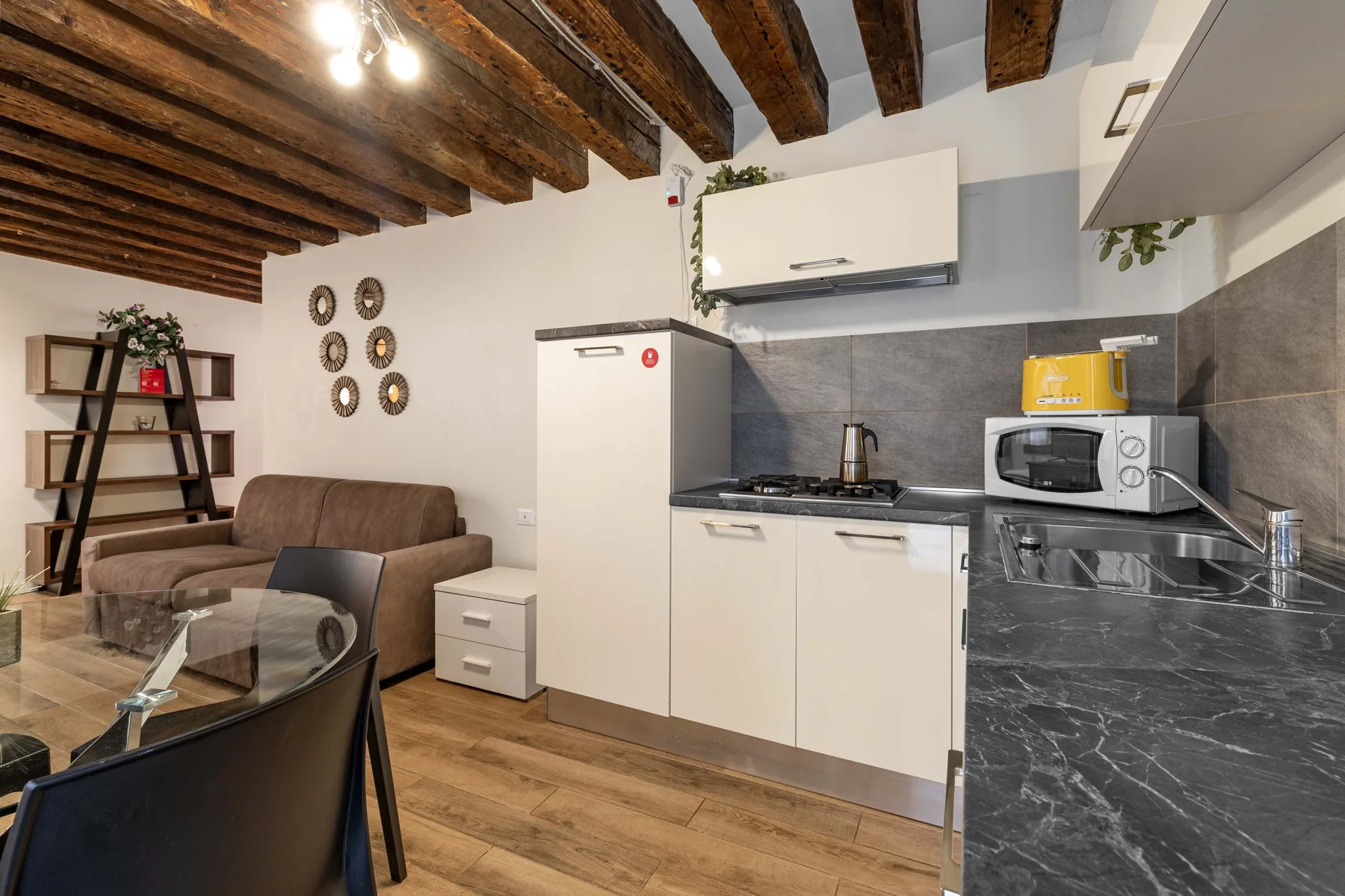 A kitchen and living area with a counter, microwave, and seating.