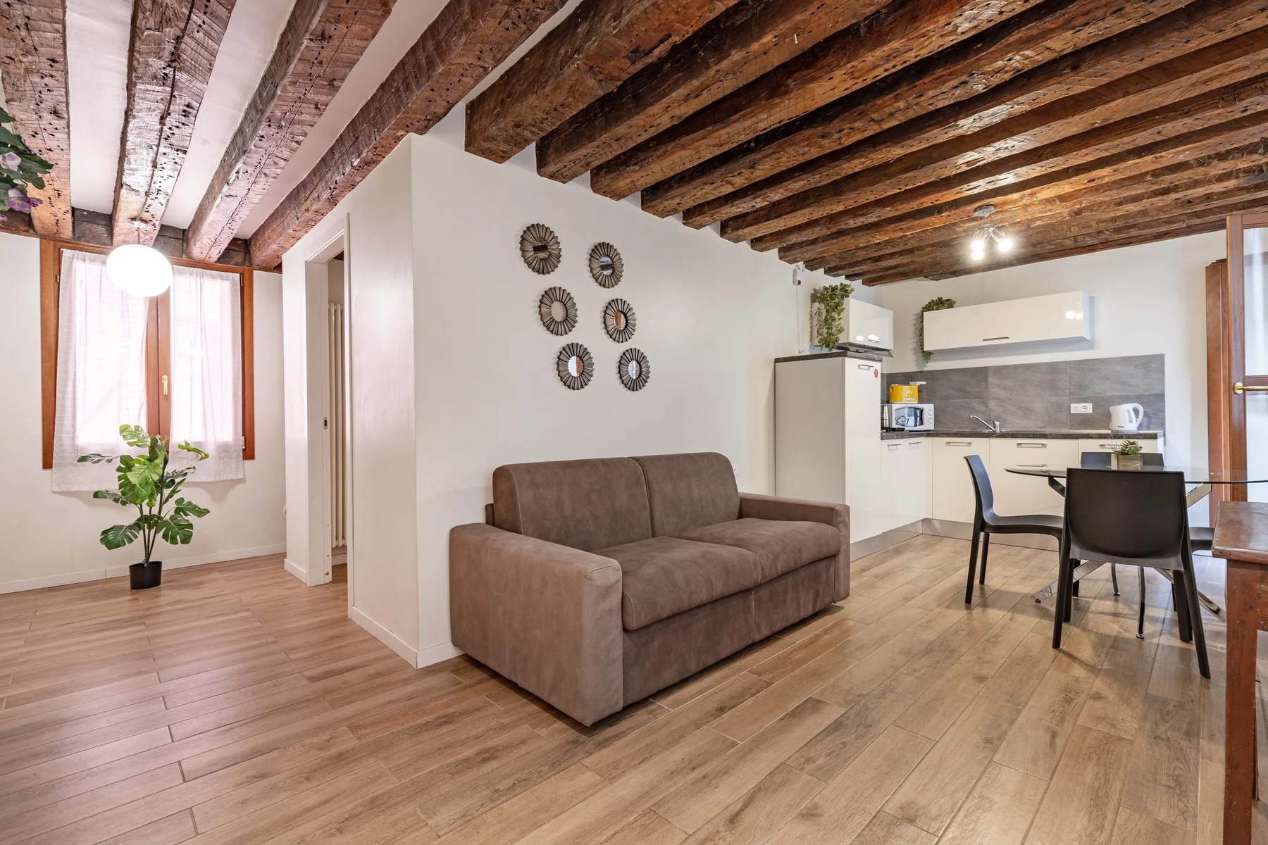 A living area with a sofa beside a small dining table and kitchenette.