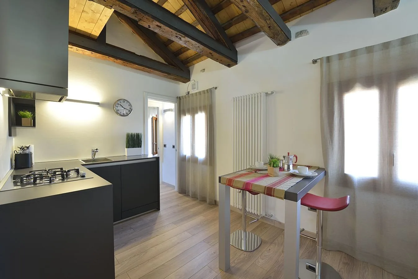 Una cocina y comedor con una encimera, una mesa y vigas de madera expuestas en el techo.