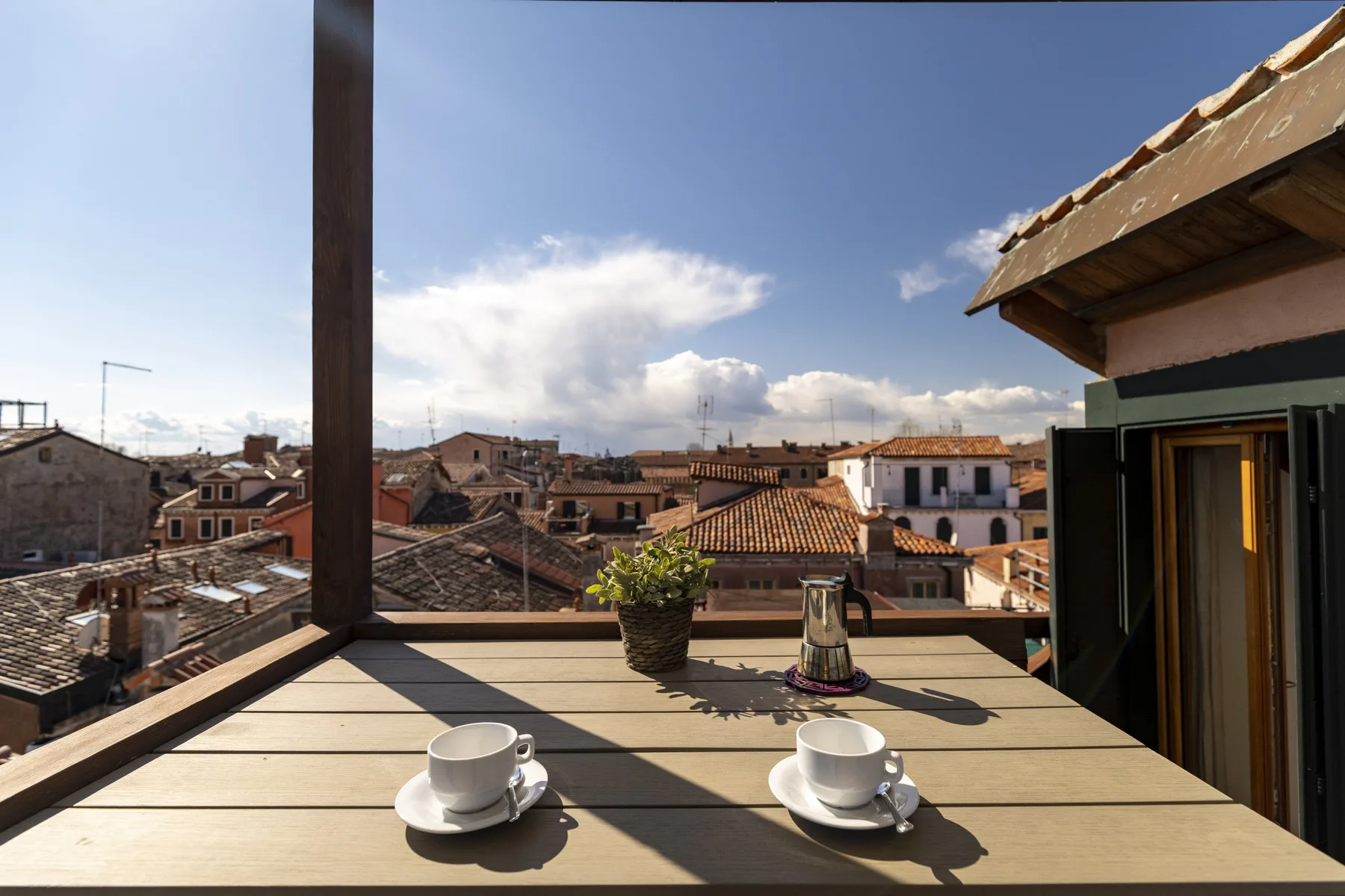 Una terraza en la azotea mira hacia edificios cercanos, con dos tazas sobre una mesa.