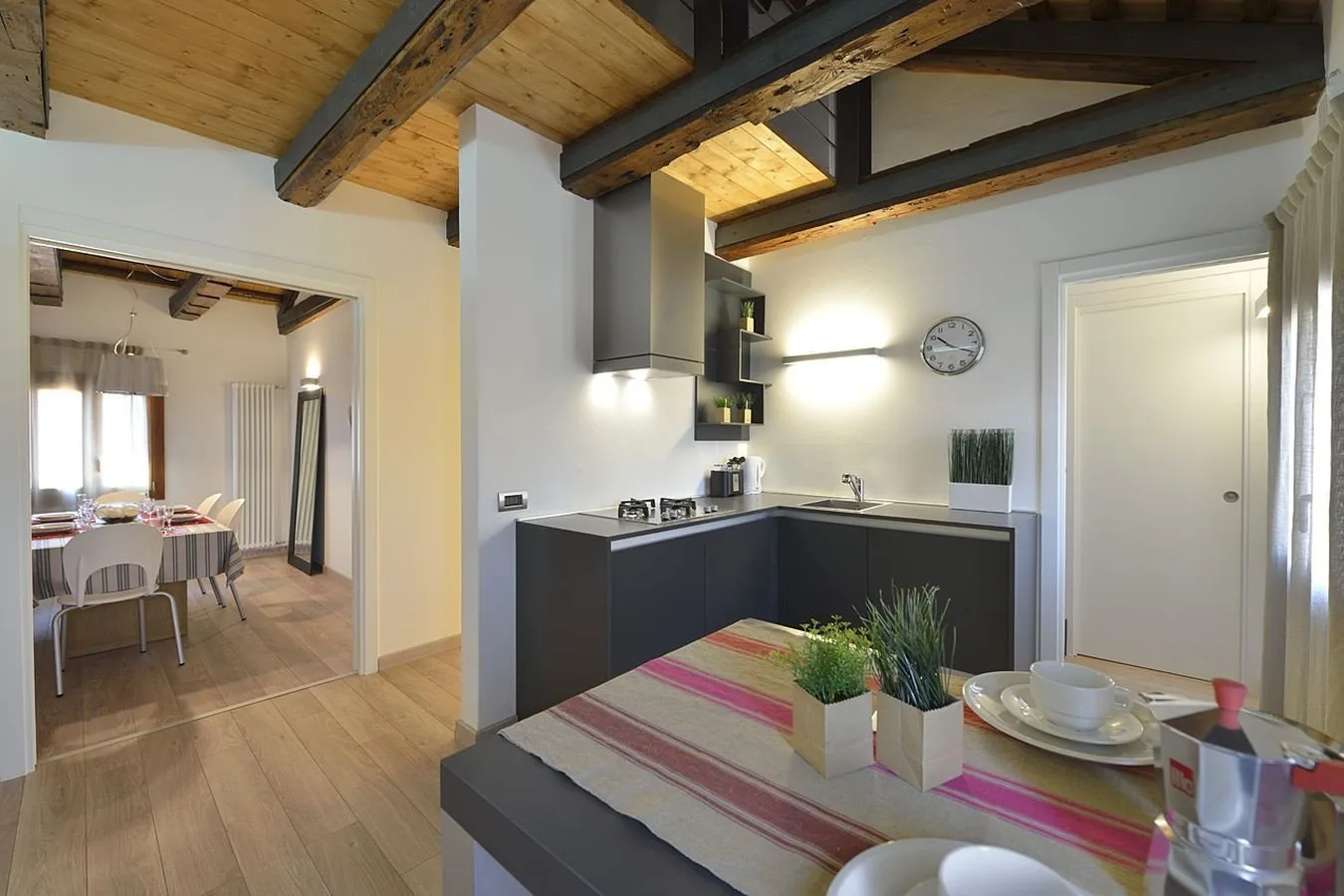 Una cocina con gabinetes oscuros y una mesa de comedor en primer plano.