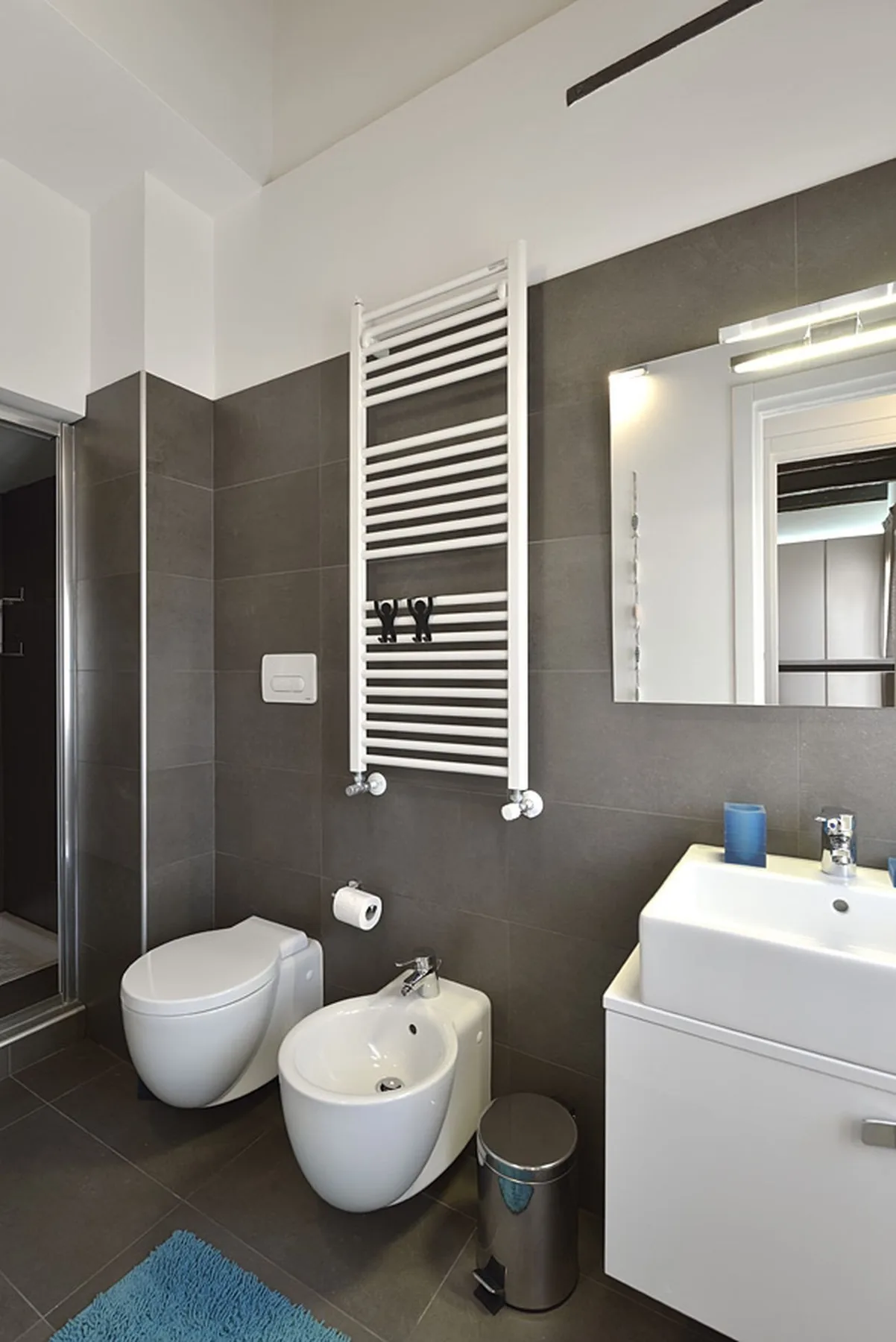 Un baño moderno con un toallero mural y sanitarios blancos.