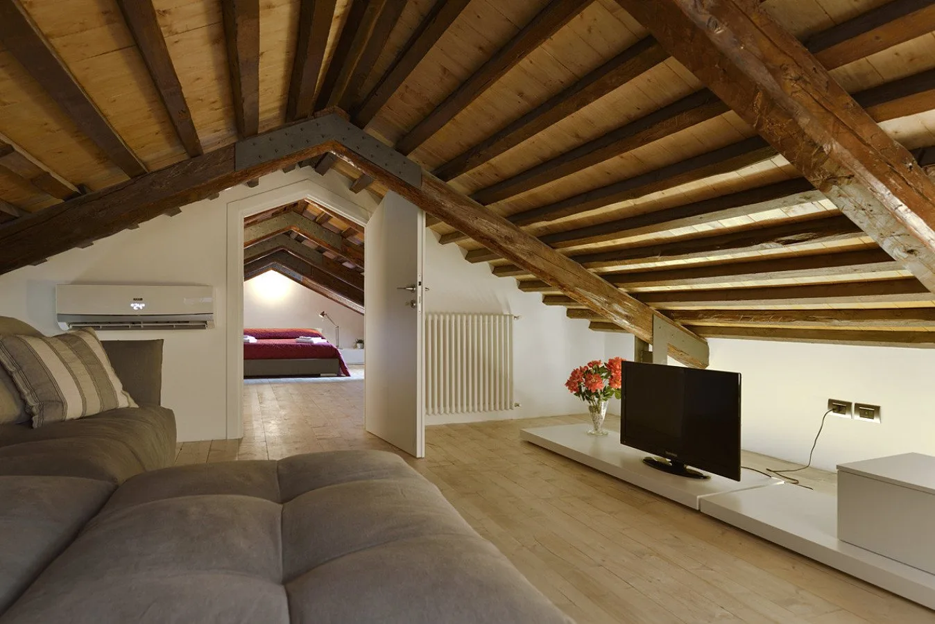 Una sala de estar con asientos y un televisor bajo vigas de madera expuestas.