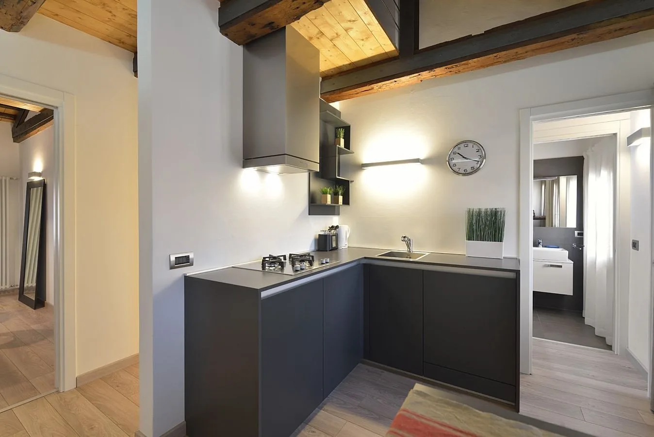 Una cocina moderna con gabinetes oscuros y una encimera bajo vigas de madera expuestas.