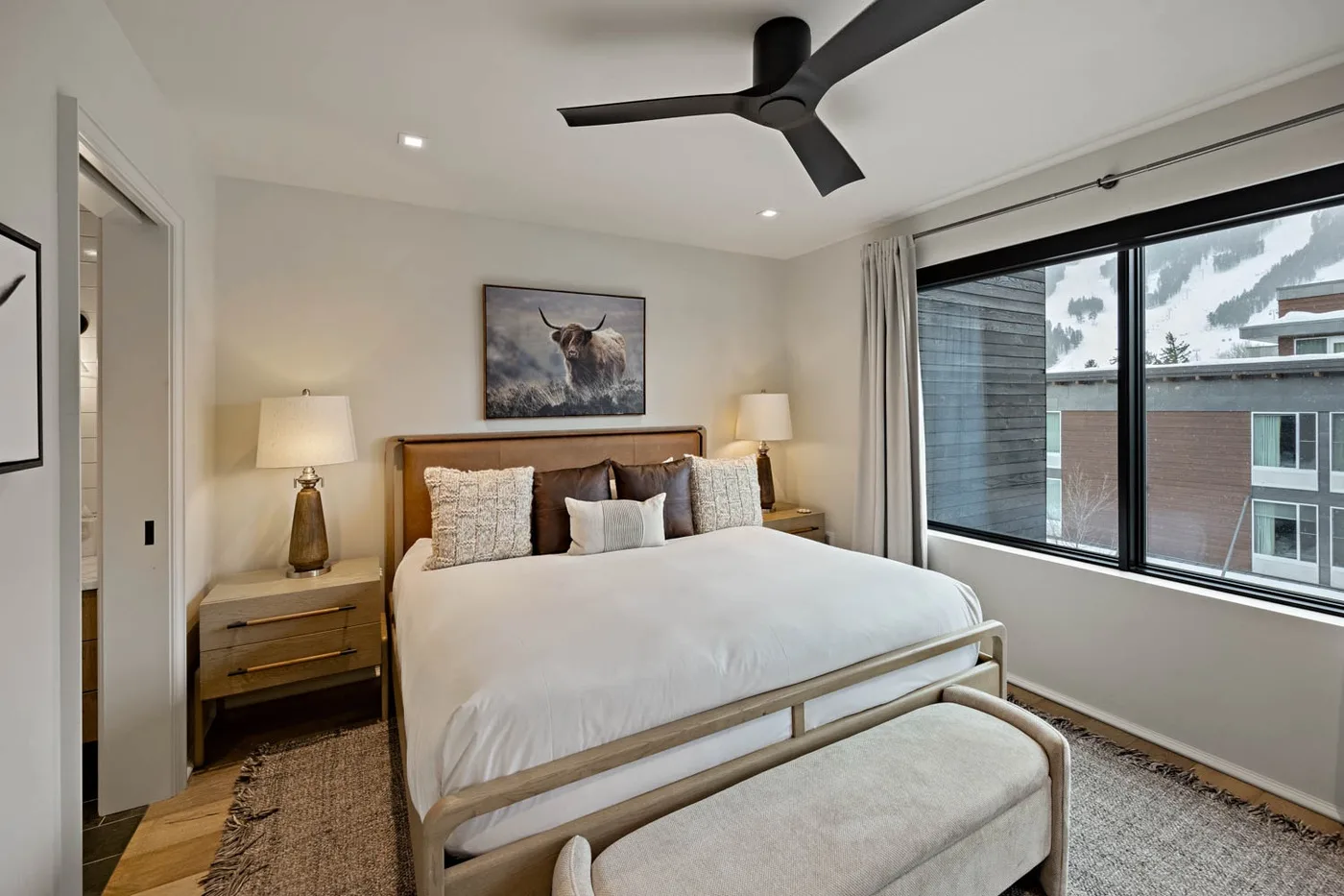 A bedroom with a neatly made bed and a large window.