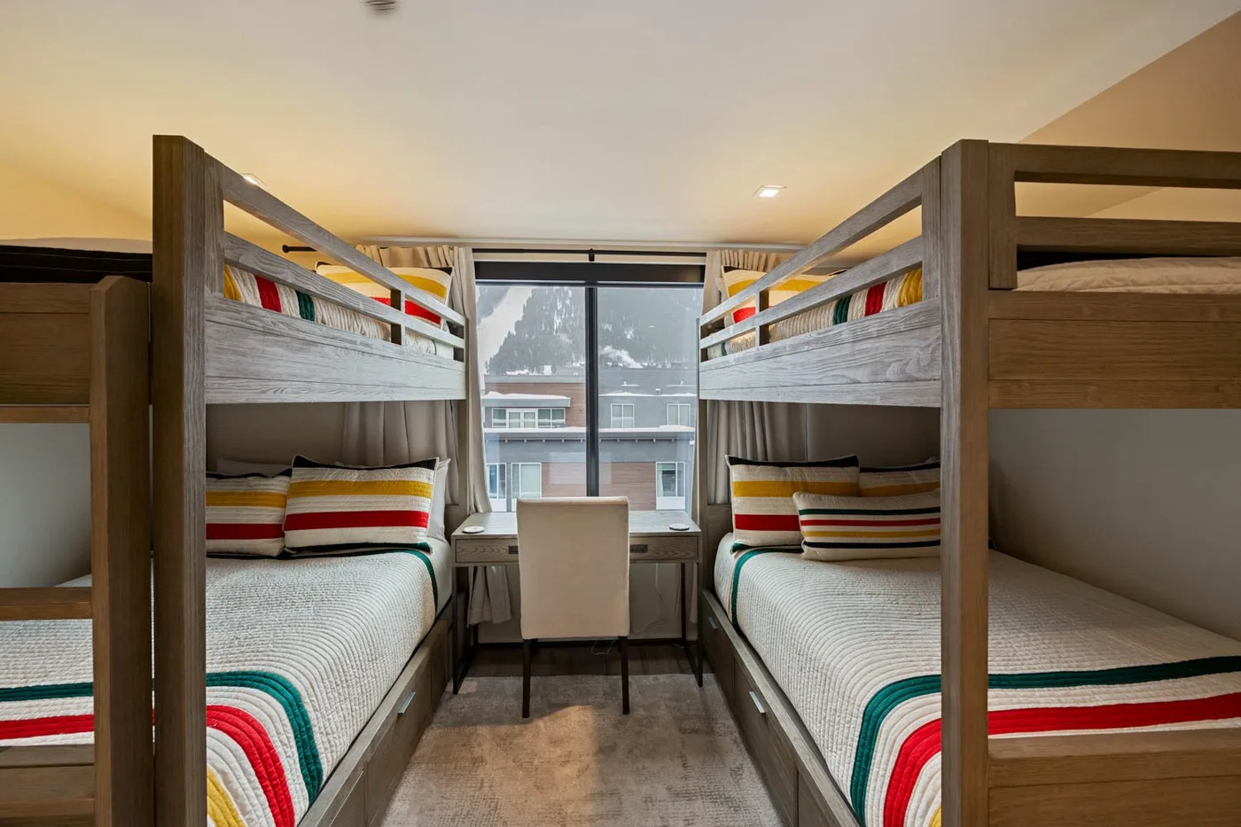 A bedroom with two sets of bunk beds and a large window.